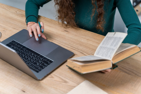 girl transcriping from book to a computer